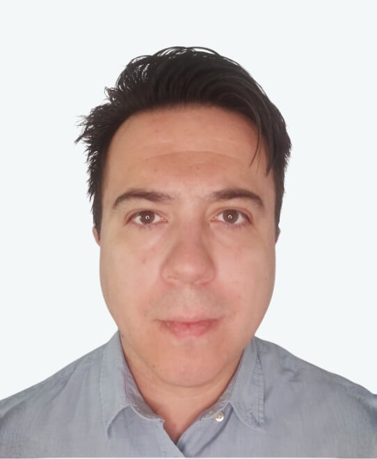 A man with short dark hair and a light blue collared shirt, representing Team V2, looks directly at the camera against a plain white background.