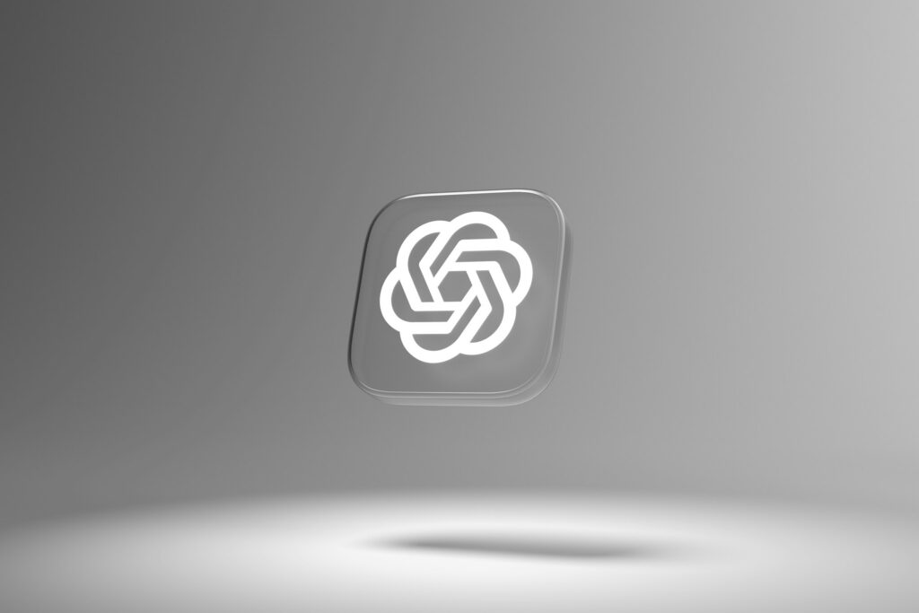 A transparent 3D square with the OpenAI logo in white is suspended over a light gray background with a shadow below, evoking structural patterns ideal for an AI ready website.