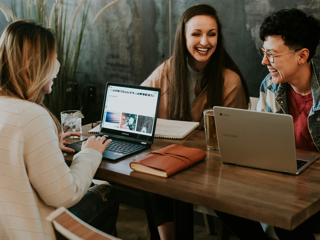 Three search professionals with laptops sitting at a desk image. Photo by Brooke Cagle on Unsplash.